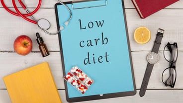 Clipboard with text Low carb diet stethoscope books pills fruits eyeglasses and watch