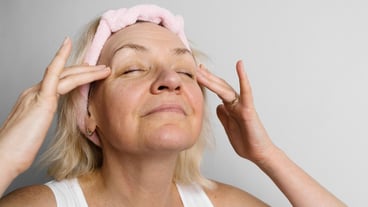 Mid age woman with blond hair doing face self massage and yoga Self care for 50s female