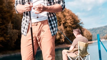Adult grandson fishing with grandfather on jetty