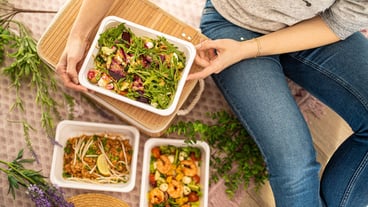 Girl hands are holding plastic container salad with rucola beetroot and feta cheese. food delivery concept. unrecognizable people